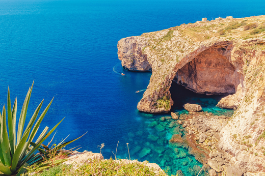 Malta Blue Grotto Pleasure boat with tourists runs. Natural arch